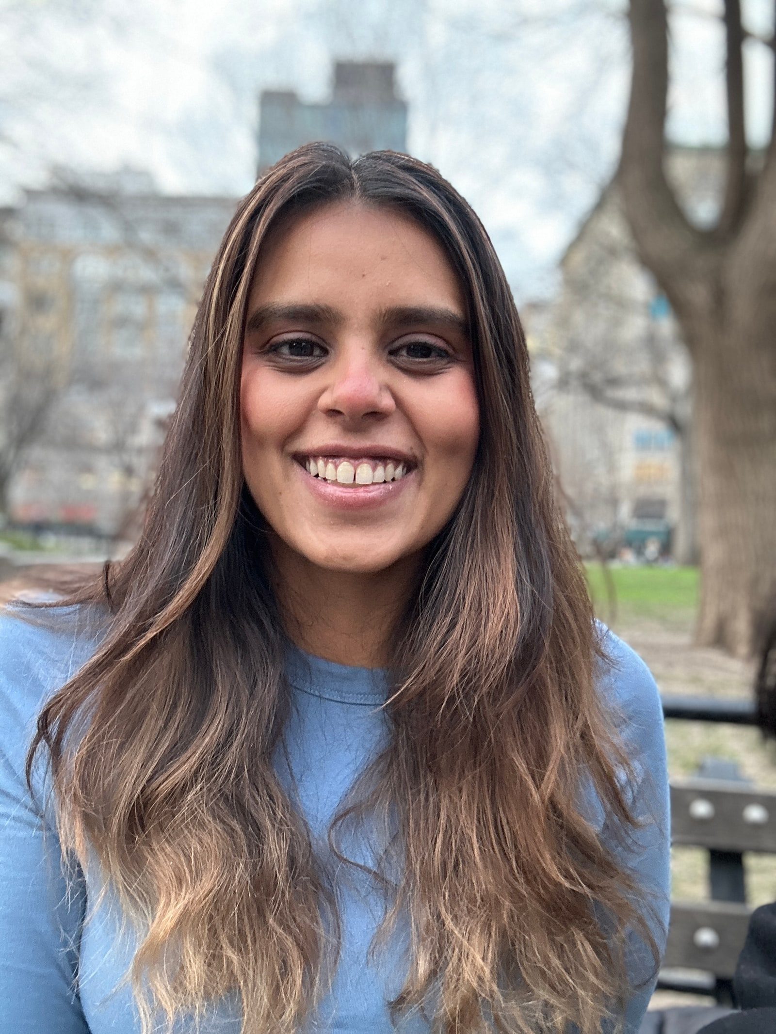Portrait of Shalakha Jain, smiling outdoors in a light blue sweater.
